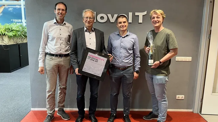Four members of the CarbSorbTec team at Novel-T, holding a framed certificate naming CarbSorbTec B.V. an official University of Twente spin-off and a bottle of champagne